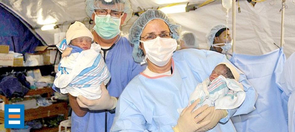 Doctors hold babies delivered in BLU-MED Mobile Hospital OBGYN units in Haiti following a devastating 2010 earthquake.