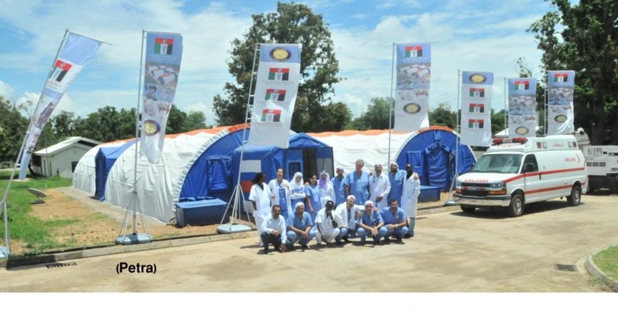 Medical team poses outside fabric hospital structures