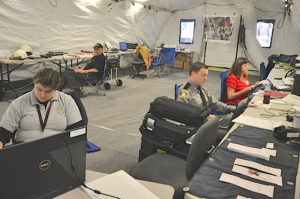 An emergency response team uses a BLU-MED EXT Medical Trailer System shelter as a command center. 