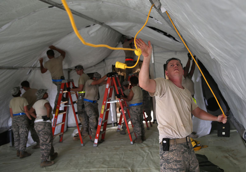 soldier hanging cable inside field hospital fabric building